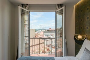 Ein Hotelzimmer mit Balkon, einem Bett, einem Kopfteil und Blick auf die Stadtlandschaft.