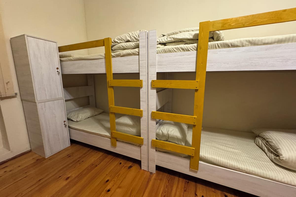 Quarto com beliche, armário e piso de madeira.
