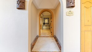 A hallway with a marble floor, an arched doorway, and a yellow door. - Premium Ocean Views & Unbeatable Convenience: Villa La Estancia 1303 (Cabo San Lucas)