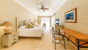A hotel room with a bed, a desk, a chair, a television, and a ceiling fan. - Premium Ocean Views & Unbeatable Convenience: Villa La Estancia 1303 (Cabo San Lucas)