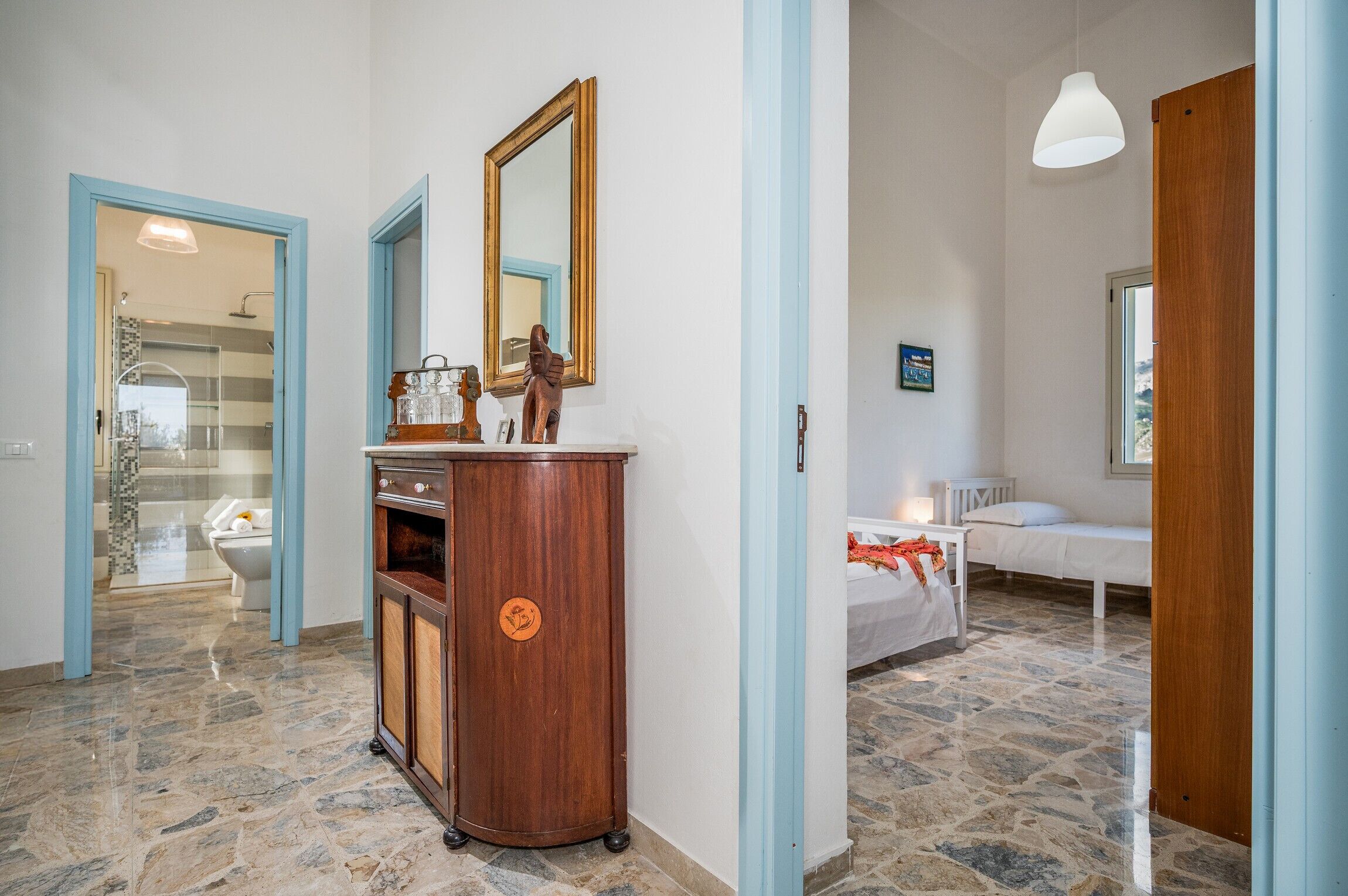 A bedroom with a bed, a bedside table, a mirror, and a wooden cabinet.
