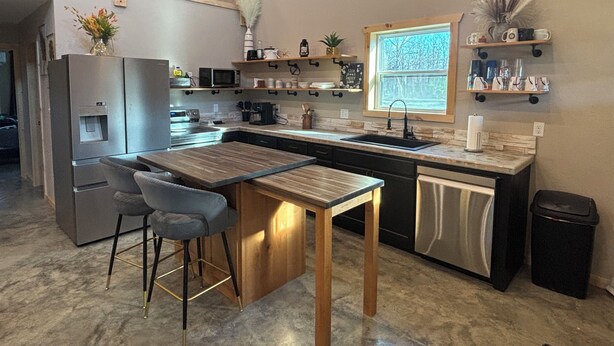 A modern kitchen with a bar area, stainless steel appliances, and a window with a view.