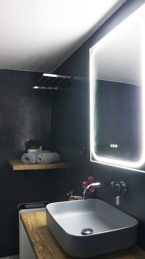 Een moderne badkamer met een grote spiegel, een wastafel en een plank met handdoeken.