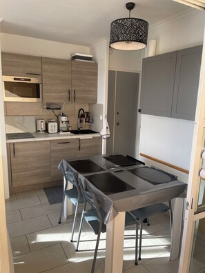 A modern kitchen with wooden cabinets, a built-in microwave, a coffee machine, and a dining table with chairs. - ✨Cap Estérel Agay T2 / Magnificent Sea View / Air-conditioned / Access Parking-Pools✨ (Saint-Raphaël)