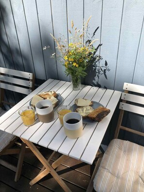 Uma mesa com itens de café da manhã, um vaso com flores e cadeiras de madeira.