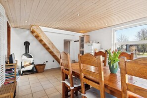 Ein Essbereich mit Holztisch und Stühlen, einem Kamin und Blick durch ein Fenster.