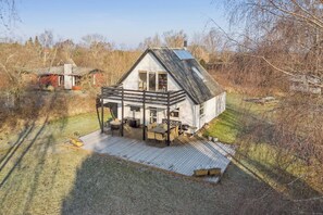 Ein Haus mit Terrasse, Schornstein und einer Solaranlage.