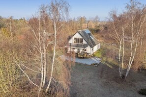 Et hus med skråtag, balkon og en synlig terrasse.