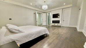 Une chambre à coucher moderne avec un grand lit, un téléviseur fixé au mur et un dressing.