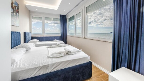 Una habitación de hotel moderna con una cama grande, dos mesitas de noche y vistas al mar.