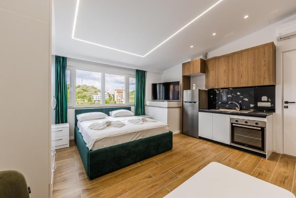 Une chambre d’hôtel moderne équipée d’un lit, d’une kitchenette et offrant une vue sur la ville.
