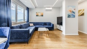 Una sala de estar moderna con un sofá seccional azul, una mesa de centro blanca y un televisor de pantalla plana.