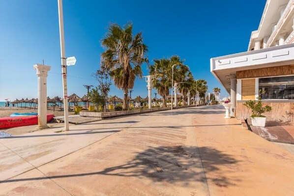 Ein Hotel direkt am Strand mit freiem Blick auf das Meer, Palmen und einem modernen Gebäude mit Restaurant.