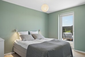 A bedroom with a bed, bedside lamps, a window, and a view of an outdoor seating area. - Magnificent seaside villa with stunning views (Hundested)