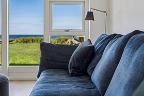 A modern living room with a view of the sea, a sofa, and a floor lamp. - Magnificent seaside villa with stunning views (Hundested)