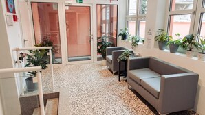 Een hal met een grijze bank, potplanten en een trap.