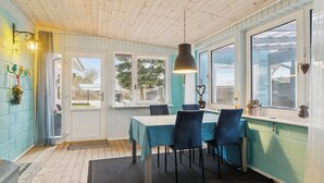 Een eethoek met een tafel, stoelen, een hanglamp en uitzicht door het raam.