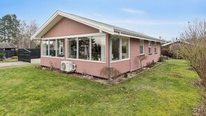 Een gelijkvloers huis met een groot raam, een klein terras en een gazon.