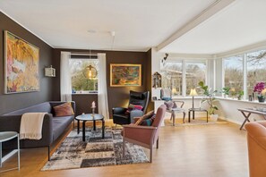 A modern living room with a sofa, chairs, a coffee table, and a large window with a view. - Relaxing holiday home close to the sea (Korsør)