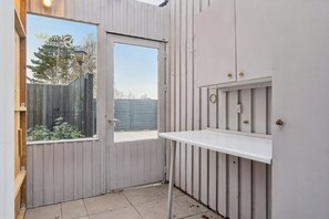 A small, enclosed outdoor area with a door, a window, and a white bench. - Relaxing holiday home close to the sea (Korsør)
