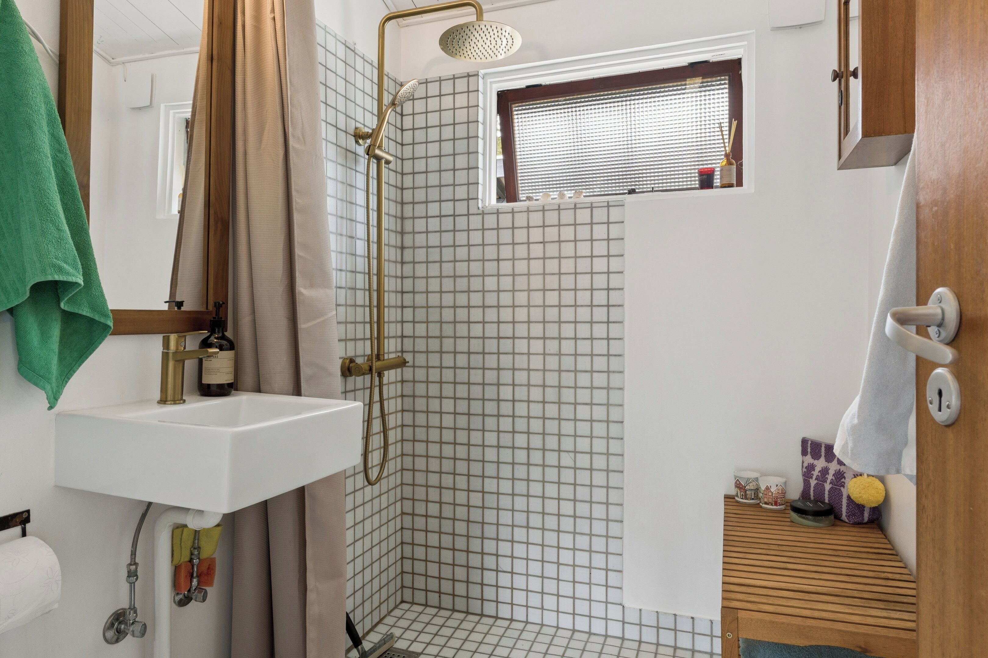 A bathroom with a shower, sink, and window.