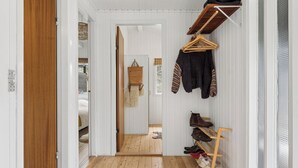 Un couloir avec un plancher en bois, un porte-chaussures et un porte-manteau.