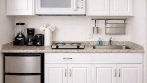 A kitchen with white cabinets, a stainless steel refrigerator, a double oven, a microwave, a coffee maker, and a sink. - Miami Beach Studio Retreat Near d Ocean (Miami Beach)