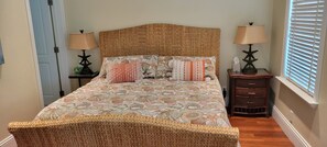 A bed with a woven headboard, a floral bedspread, and two bedside tables with lamps. - Key West Luxury Home with pool, 28 day minimum (Key West)