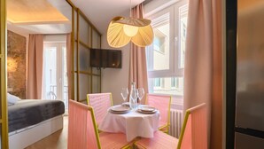 Una camera d'albergo con un letto, un tavolo da pranzo con sedie, una televisione e una finestra con tende.