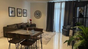 A modern living room with a dining area, a sofa, a coffee table, and a potted plant. - Embassy Onebedroom by Unique Abodes (Accra)