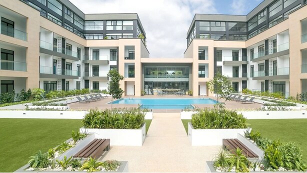 A modern building with a central pool, surrounded by well-maintained lawns and seating areas. - Embassy Onebedroom by Unique Abodes (Accra)