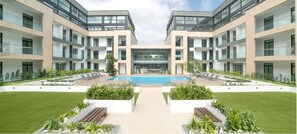 A modern building with a central pool, surrounded by well-maintained lawns and seating areas. - Embassy Onebedroom by Unique Abodes (Accra)