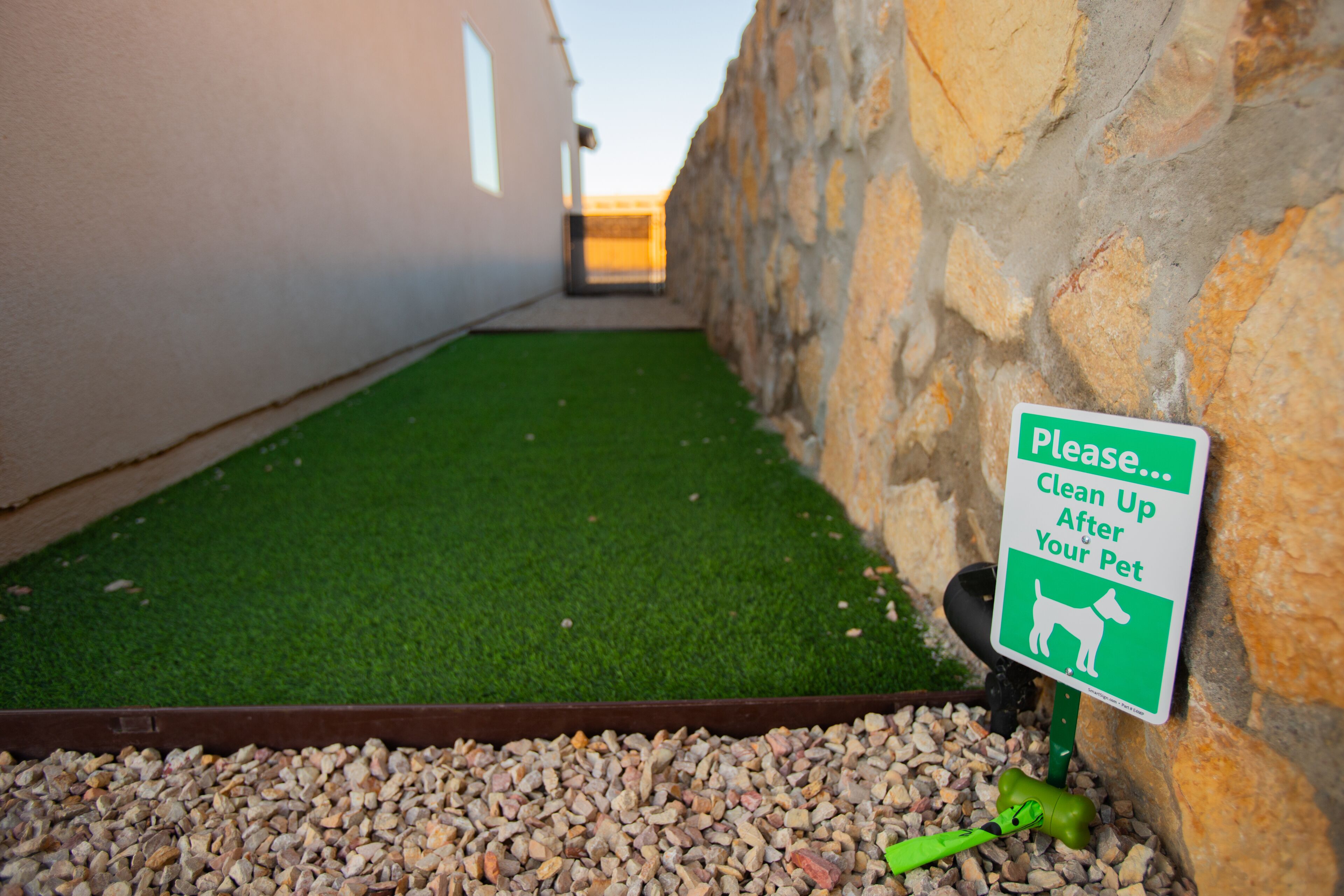 A green artificial turf area with a sign instructing to clean up after pets.