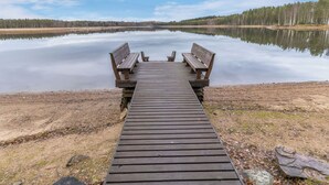 Une jetée en bois qui mène à un lac paisible, avec des bancs et une table de pique-nique.