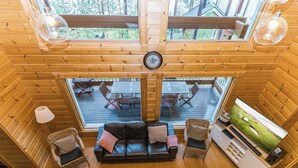 A cozy cabin interior with a wooden interior, a sofa set, a dining area, and a large window overlooking a deck. - Villa maaria by Interhome (Juva)
