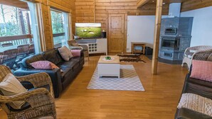 A cozy living room with a wooden floor, a leather sofa, wicker chairs, a coffee table, and a television. - Villa maaria by Interhome (Juva)