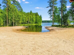 Une plage de sable bordée d’un lac paisible, le tout entouré d’une végétation luxuriante.