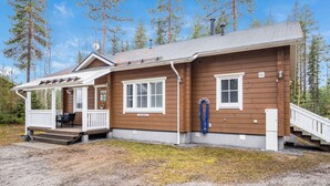 Een houten chalet met een veranda, een overdekt terras en een trap naar een terras.