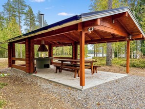 Un espace extérieur abrité, équipé d’une table de pique-nique et d’un barbecue.