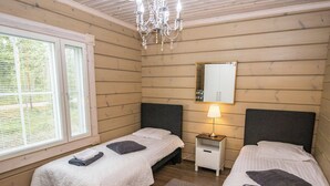 Een kamer met twee bedden, een nachtkastje met een lamp, een spiegel en een kroonluchter.