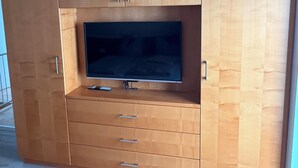 Een houten entertainmentkast met een flatscreen televisie, lades en kastjes.