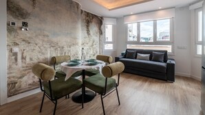 Un soggiorno moderno con zona pranzo, un divano grigio e un murale sulla parete.
