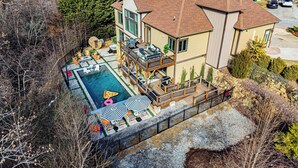A large house with a swimming pool, outdoor furniture, and a deck.