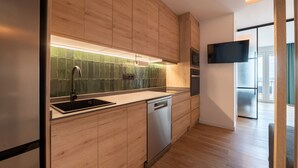 A modern kitchen with wooden cabinets, a stainless steel sink, and a dishwasher. - GRAN VIA capitals, MADAGASCAr (Madrid)