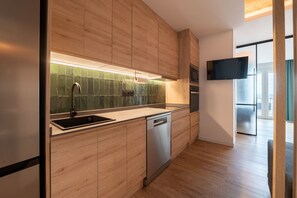 A modern kitchen with wooden cabinets, a stainless steel sink, and a dishwasher. - GRAN VIA capitals, MADAGASCAr (Madrid)