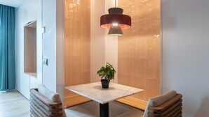 A modern dining area with a table and two chairs, a pendant light, and a potted plant. - GRAN VIA capitals, MADAGASCAr (Madrid)