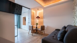 A modern living room with a sofa, a dining table with chairs, and a TV mounted on the wall. - GRAN VIA capitals, MADAGASCAr (Madrid)