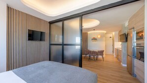 A modern hotel room with a bed, a dining area, and a kitchen. - GRAN VIA capitals,ISLAS MAURICiO (Madrid)