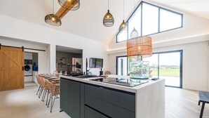A modern kitchen with a large island, pendant lighting, and a view to the outdoors.