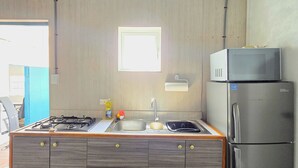 A modern kitchen with a built-in gas stove, stainless steel sink, and a double-door refrigerator. - Studio Cadushi, Walking - 10 min from the beach (Noord)